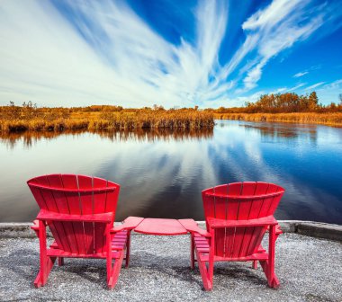 Cirrus bulutlar Winnipeg nehre yansıtılır. Dinlenmek için hoş bir yer. Nehir üzerinde iki kırmızı plaj sandalye. Eski Canada Barajı Park. Ekolojik ve eğlence turizmi kavramı