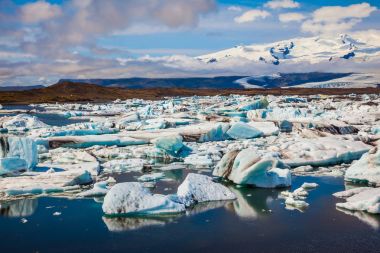 Buzlar ve içinde yansıyan mavi su buz jokulsarlon gölünde bulutlu gün yüzey. Aşırı Kuzey turizm kavramı  