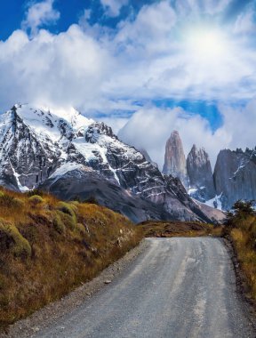 Efsanevi taş Torres karla kaplı siyah kayalarla çevrili. Bunlar toprak yol açar. Milli Parkı Torres del Paine. Şili'seyahat. Aktif ve aşırı turizm kavramı