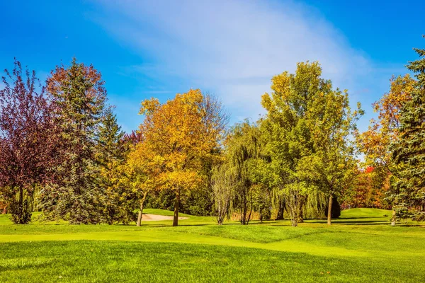 The concept of active and Golf tourism. Golf Club in French Canada. Green grass golf course is surrounded by scenic autumn park