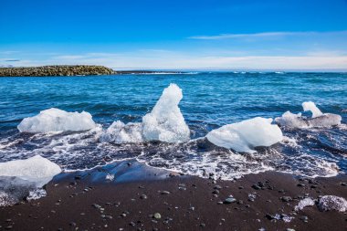 Okyanus kıyısında buz Lagoon - Jokulsarlon. İzlanda. Beach siyah ve kahverengi kum tuhaf buz parçaları ile kaplı. Aşırı Kuzey turizm kavramı