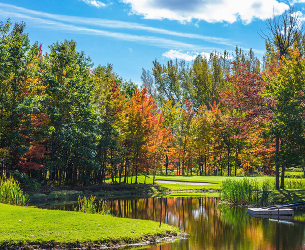 Concept of Golf tourism. Red, orange and green autumn foliage near lake 