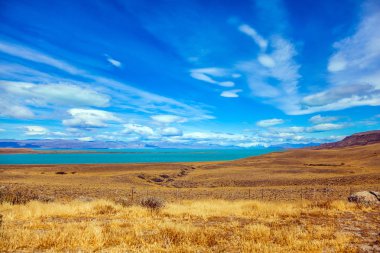 Aktif ve egzotik turizm kavramı. Sığ göl ve sararmış ot ile düz düz. Patagonya Pampa. Güçlü Rüzgar bulutlar taşır