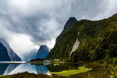 Yeni Zelanda. Milford Sound 'un ünlü okyanusu üzerindeki fırtına bulutları gökyüzünü kaplıyor. Turist gemileri, yatlar ve tekneler. Ekolojik, aktif ve fotografik turizm kavramı