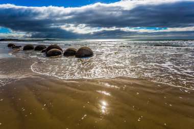 Moeraki Boulders - Koekokhe sahilinde büyük küresel kayalar. Okyanus akıntısı. Yeni Zelanda 'ya git. Aktif, eko ve fotoğraf turizmi kavramı