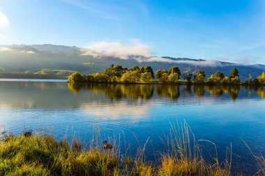 Queenstown yolunda kocaman sessiz bir göl var. Vahşi ördekler yumuşak suda yüzer. Sabah erkenden. Yeni Zelanda 'nın manzaralı yerleri. Aktif, ekolojik ve fotoğraf turizmi kavramı