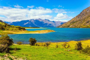 Muhteşem Hawea Gölü 'nü çevreleyen yeşil çimenli dağlar. Güney Adası, Yeni Zelanda. Dünya 'nın sonuna yolculuk. Ekolojik, aktif ve fotoğraf turizmi kavramı