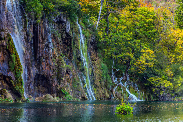 Travel to the Plitvice Lakes. Several picturesque waterfalls flowing into the karst lake with emerald water. The concept of ecological, active and phototourism. Autumn in Croatia