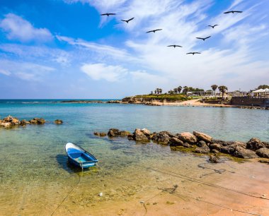 Balıkçı teknesi demirli. Caesarea, İsrail 'in antik askeri tahkimatlarının deniz yıkıntıları sel altında kaldı. Göçmen kuş sürüsü gökyüzünde uçuyor. Arkeolojik ve tarihi turizm kavramı 