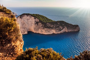 Akdeniz 'deki sihirli ada. Küçük kumlu bir sahili olan tenha bir koy. Gökyüzü sıcak bir günbatımı parlıyor. Yaz tatili ve fotoğraf turizmi konsepti