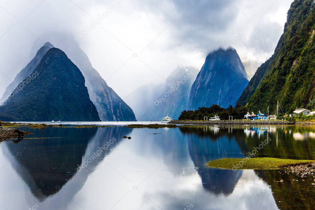 Land of hobbits - New Zealand. Port of tourist and pleasure ships, yachts and boats. Storm clouds cover the sky over the ocean fjord Milford Sound.  Concept of exotic, ecological and photographic tourism