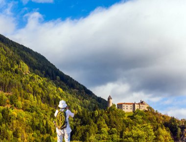 Sırt çantalı orta yaşlı bir kadın Dolomitlerdeki güzel bir manzaranın fotoğraflarını çekiyor. Güney Tyrol 'da harika bir gün. Ekolojik ve fotoğraf turizmi kavramı