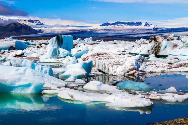 The ice is covered in volcanic ash. White and blue icebergs and ice floes reflected in the water. The lagoon Jokulsaurloun in Iceland. The concept of extreme, northern and photo tourism