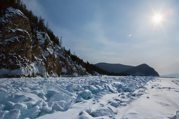 Sun over clumps of blue ice on the snow. Beautiful winter landscape in Lake Baikal. Royalty Free Stock Images