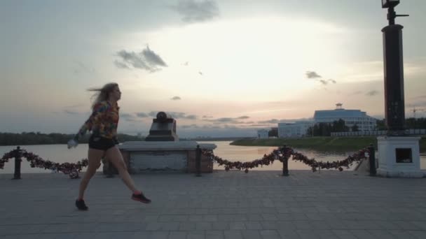 Gyönyörű lány akrobatikus tánc töltésen naplemente stock footage videóinak — Stock videók