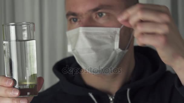 Zieke man in medische masker lost de bruistablet in een glas water slowmotion stock footage video — Stockvideo