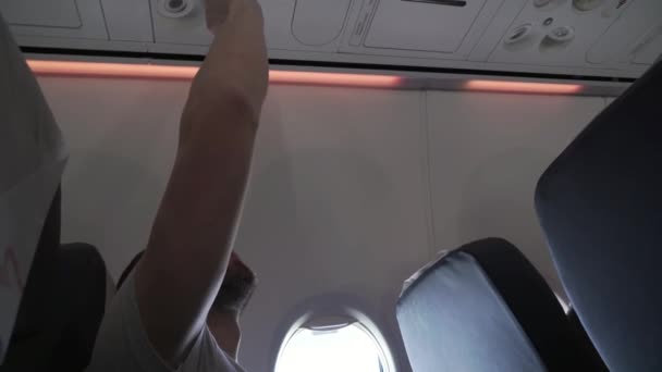 Чоловік сидить біля вікна літаючий літак і регулює потік повітря з особистого кондиціонера відеозйомки — стокове відео