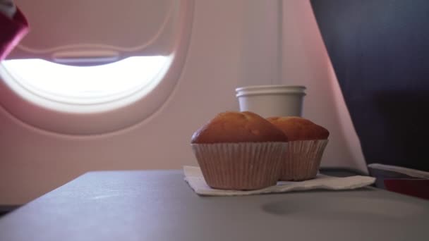 Женщина ест торт и пьет напиток из бумажной чашки за столом летит самолет акции видео — стоковое видео