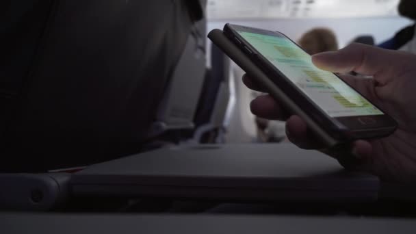 Frau sitzt in fliegendem Flugzeug und hat Spaß mit Smartphone — Stockvideo