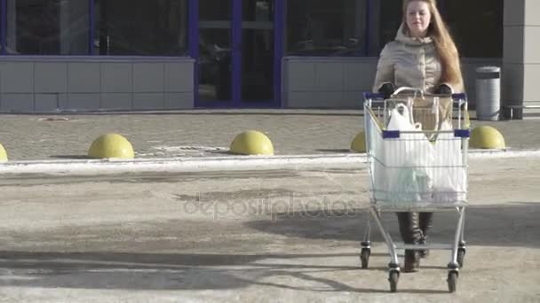 Jovencita saca carrito con las compras del vídeo de archivo de stock del supermercado — Vídeos de Stock