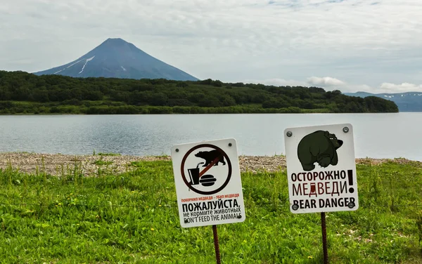 标志警告危险的满足游客与背景，千岛湖和 Ilyinsky 火山熊. — 图库照片