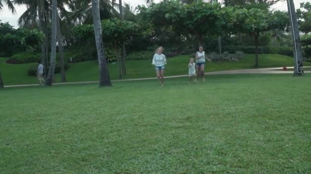 Feliz madre con hijas felizmente ejecutar a través de verde césped cámara lenta material de archivo de vídeo — Vídeos de Stock