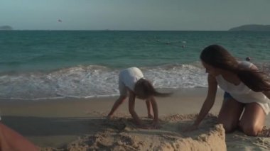 Mutlu anne ve kızları Güney Çin Denizi yavaş hareket hisse senedi görüntüleri video sahilde kumdan bir kale inşa