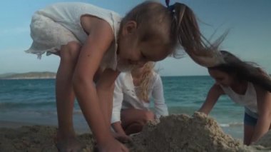 Mutlu anne ve kızları Güney Çin Denizi yavaş hareket hisse senedi görüntüleri video sahilde kumdan bir kale inşa