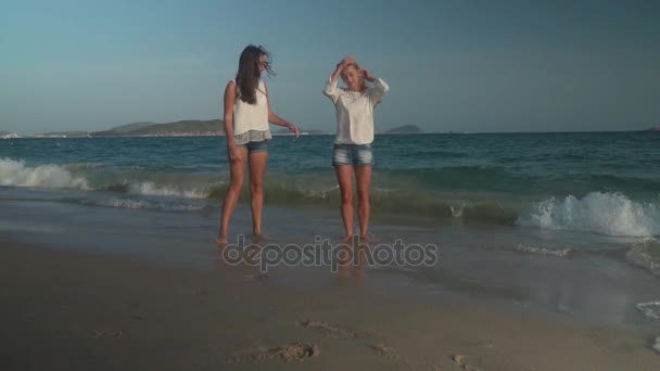 Twee mooie meisjes ontsnappen aan de golven van de Zuid-Chinese Zee, Yalong Bay slowmotion stock footage video — Stockvideo