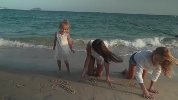 Ευτυχισμένη μητέρα και κόρες είναι ζωγραφική πάνω στην άμμο της παραλία της νότιας θάλασσας της Κίνας στοκ πλάνα βίντεο — Αρχείο Βίντεο