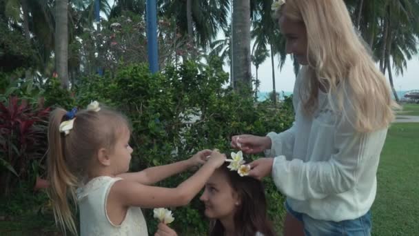 Moeder siert dochters haar met bloemen van de Plumeria slowmotion stock footage video — Stockvideo