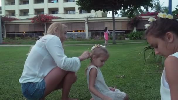 Moeder siert dochters haar met bloemen van de Plumeria stock footage video — Stockvideo