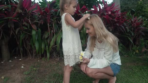 少女花プルメリア スローモーション映像ビデオで母親の髪を飾る — ストック動画