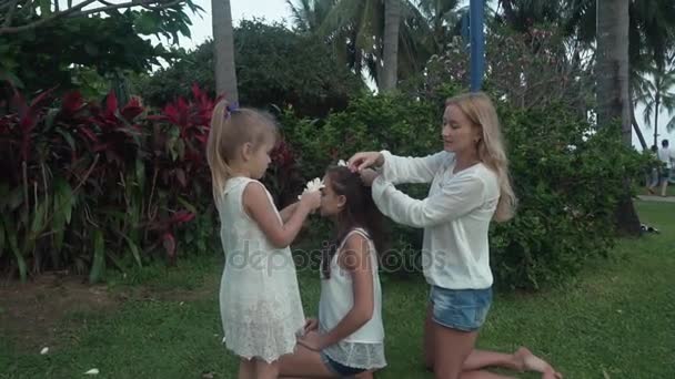 Мама украшает дочерей волосы цветами Plumeria фондового видео — стоковое видео