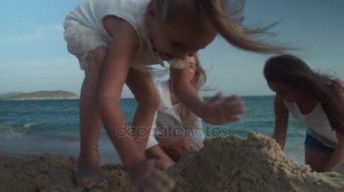 Mutlu anne ve kızları Güney Çin Denizi yavaş hareket hisse senedi görüntüleri video sahilde kumdan bir kale inşa