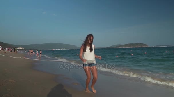 Chica joven y feliz corriendo a lo largo de la playa del Mar de China Meridional, Yalong Bay video en cámara lenta — Vídeos de Stock