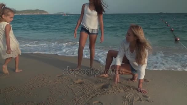 Glückliche Mutter und ihre Töchter malen auf dem Sand des Strandes von Südchina Meer Zeitlupe Stock Footage Video — Stockvideo