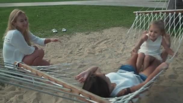 Happy mother shakes her daughters in hammock stock footage video — Stock Video