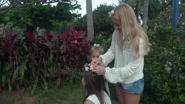 Mãe decora filhas cabelo com flores de Plumeria câmera lenta imagens de vídeo — Vídeo de Stock