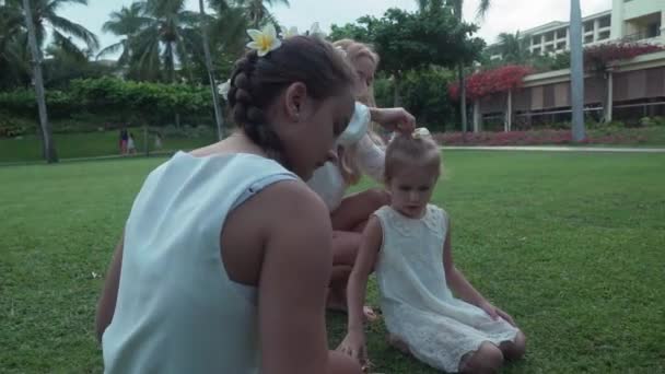 Mama zdobi włosy córki z kwiatami Plumeria Stockowy wideo — Wideo stockowe