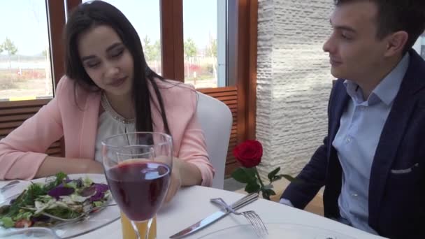 Ο τύπος δίνει το κορίτσι ένα κόκκινο τριαντάφυλλο στο εστιατόριο στο τραπέζι και φιλί Χρηματιστήριο πλάνα βίντεο αργής κίνησης — Αρχείο Βίντεο