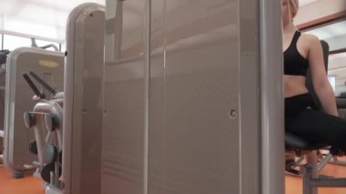 Genç kız spor salonu stok görüntüleri video simülatörde bacaklarına kaslarının Koçlar