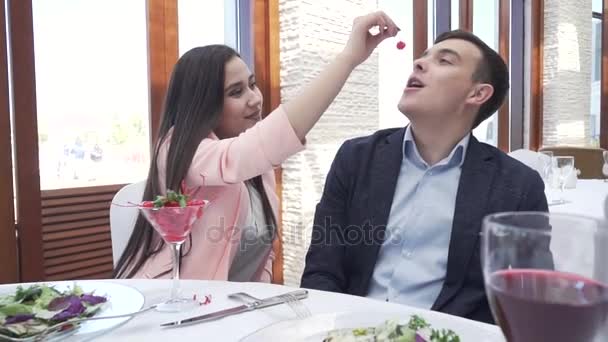 Pareja en el amor en la cena del restaurante, una chica está alimentando a un chico un vídeo de archivo de bayas — Vídeos de Stock