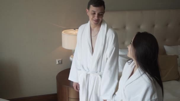 Couple aimant en manteaux blancs saute joyeusement sur le lit au ralenti stock vidéo — Video