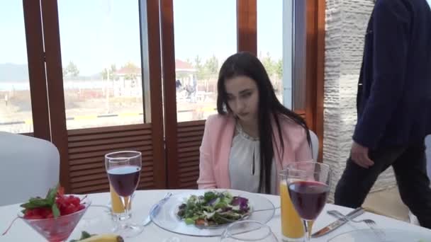 El tipo le da a la chica una rosa roja en el restaurante en la mesa y besan imágenes de archivo de vídeo — Vídeos de Stock