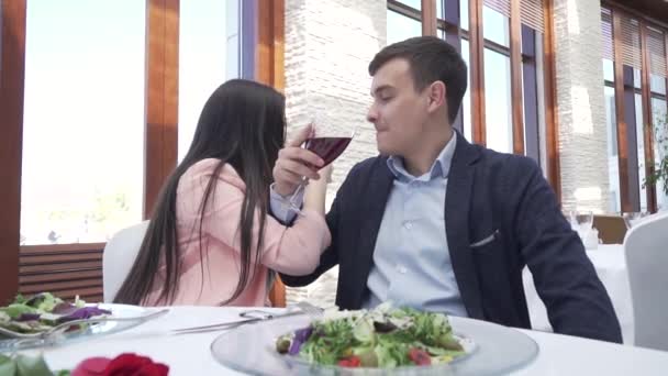Casal apaixonado no restaurante bebe um vinho tinto para irmandade e beija câmera lenta de imagens de vídeo — Vídeo de Stock