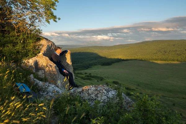 Tourist on the stone throne on the top of the Cave city Bakla in Bakhchysarai Raion — Stock Photo, Image