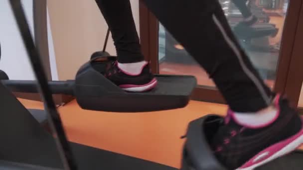Ung flicka tåg på en elliptical tränad i gym arkivfilmer video — Stockvideo