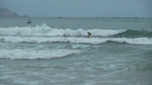 Surfers learn to conquer the big waves of the South China Sea on Dadonghai Beach stock footage video — Stock Video