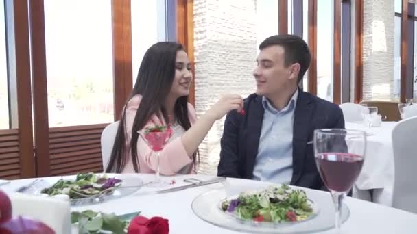 Coppia innamorata alla cena del ristorante, una ragazza sta dando a un ragazzo un filmato di frutti di bosco — Video Stock